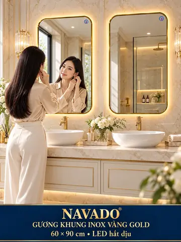 Gương khung inox vàng gold LED 60 × 90 cm — hai lavabo, đá kem và người mẫu trang phục be